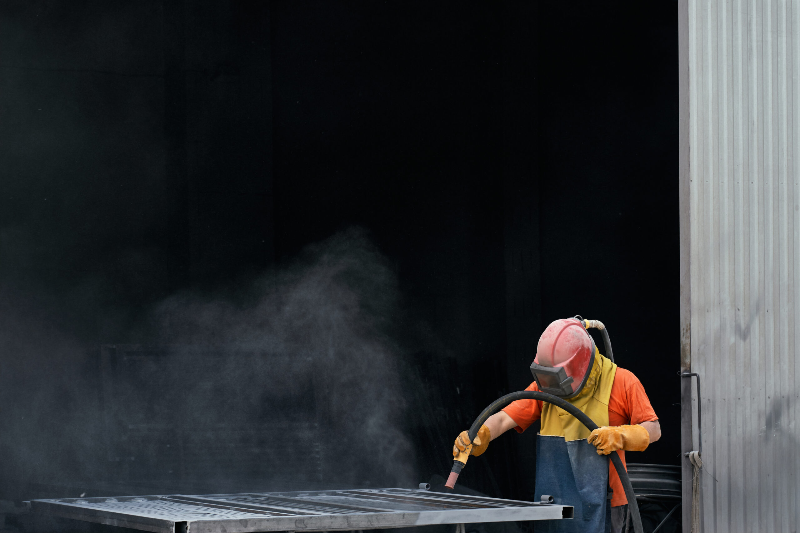 homem trabalhando com jateamento industrial