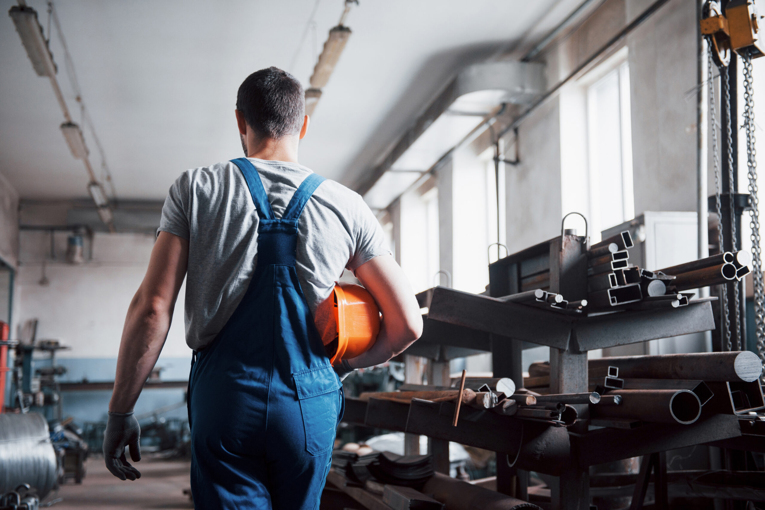 imagem ilustrativa de homem com EPIs, caminhando em uma industria